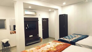 Une chambre d’hôtel équipée d’un lit, d’une télévision, d’une armoire, d’un miroir, d’une petite table et d’une chaise.