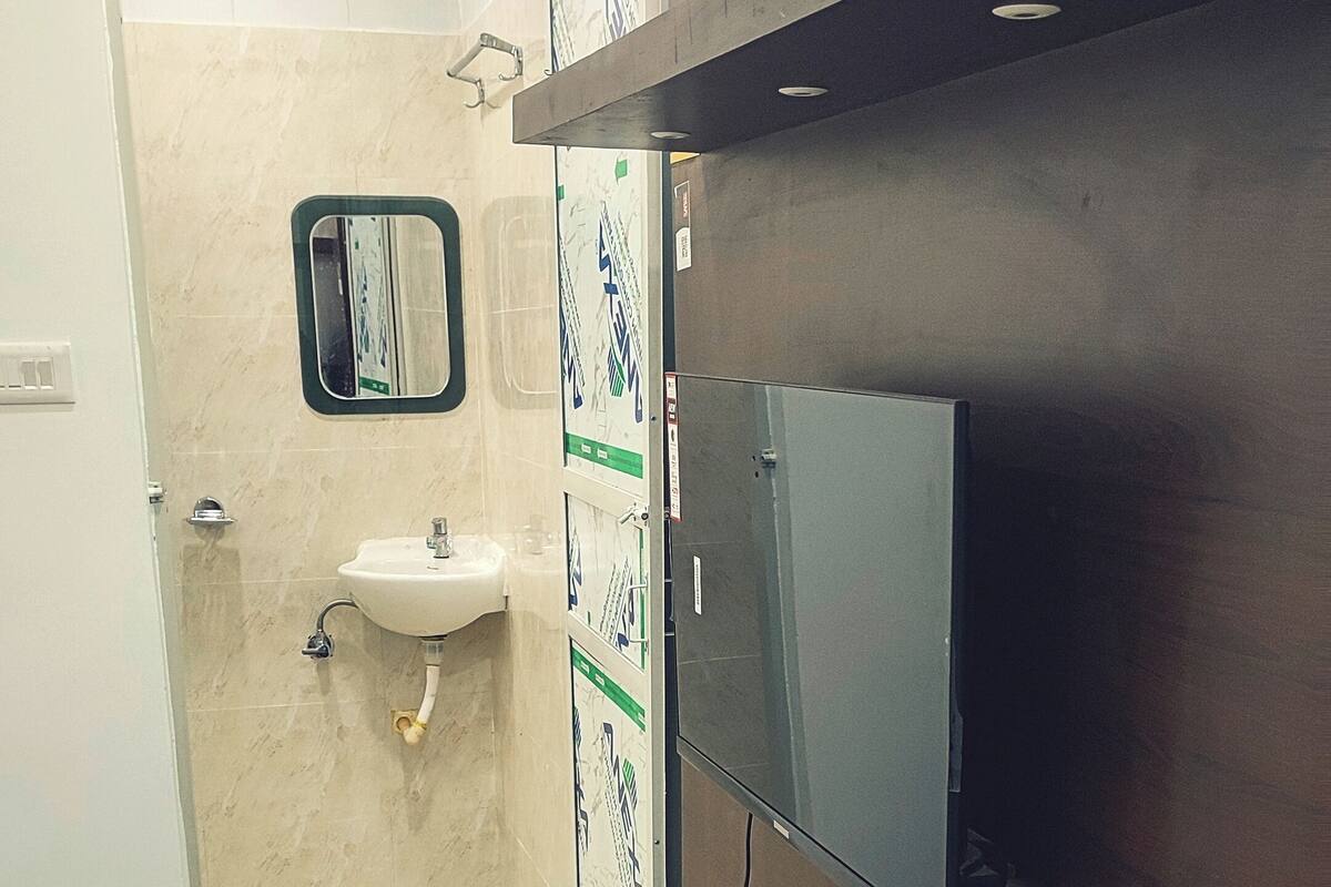 Une salle de bain équipée d’un lavabo, d’un miroir et d’un téléviseur fixé au mur.