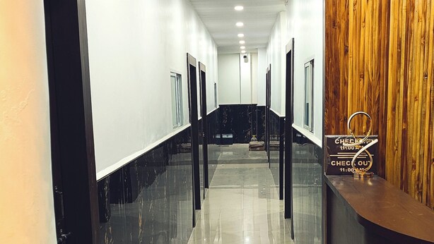 Un hall d’accueil d’hôtel comprenant un comptoir d’enregistrement, un sol carrelé en marbre et un mur revêtu de panneaux en bois.