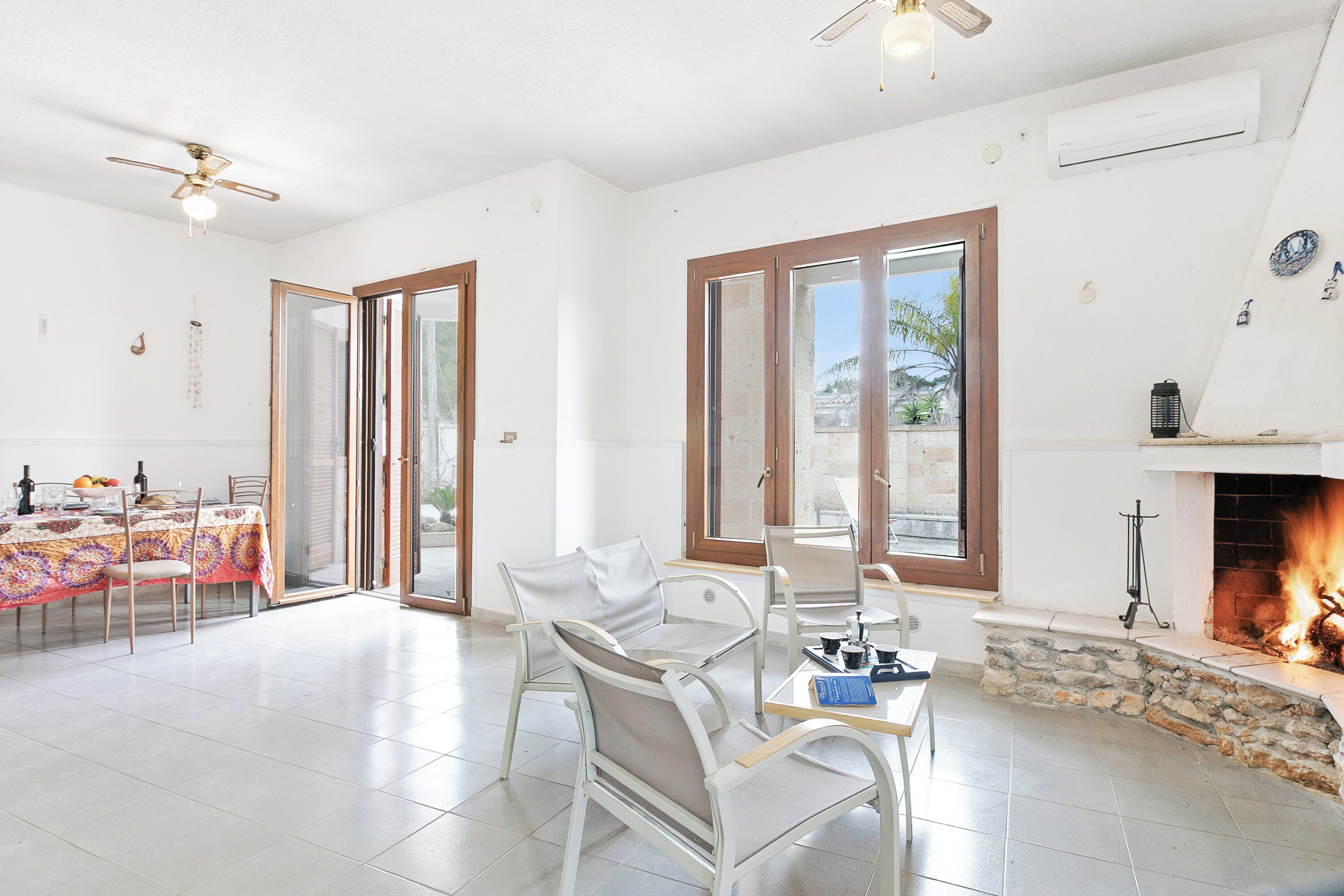 A spacious room with a fireplace, a dining area with a table set, and a seating arrangement with chairs.