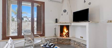 Ein Wohnzimmer mit Kamin, Fernseher und einem Tisch mit Buch und Tassen.
