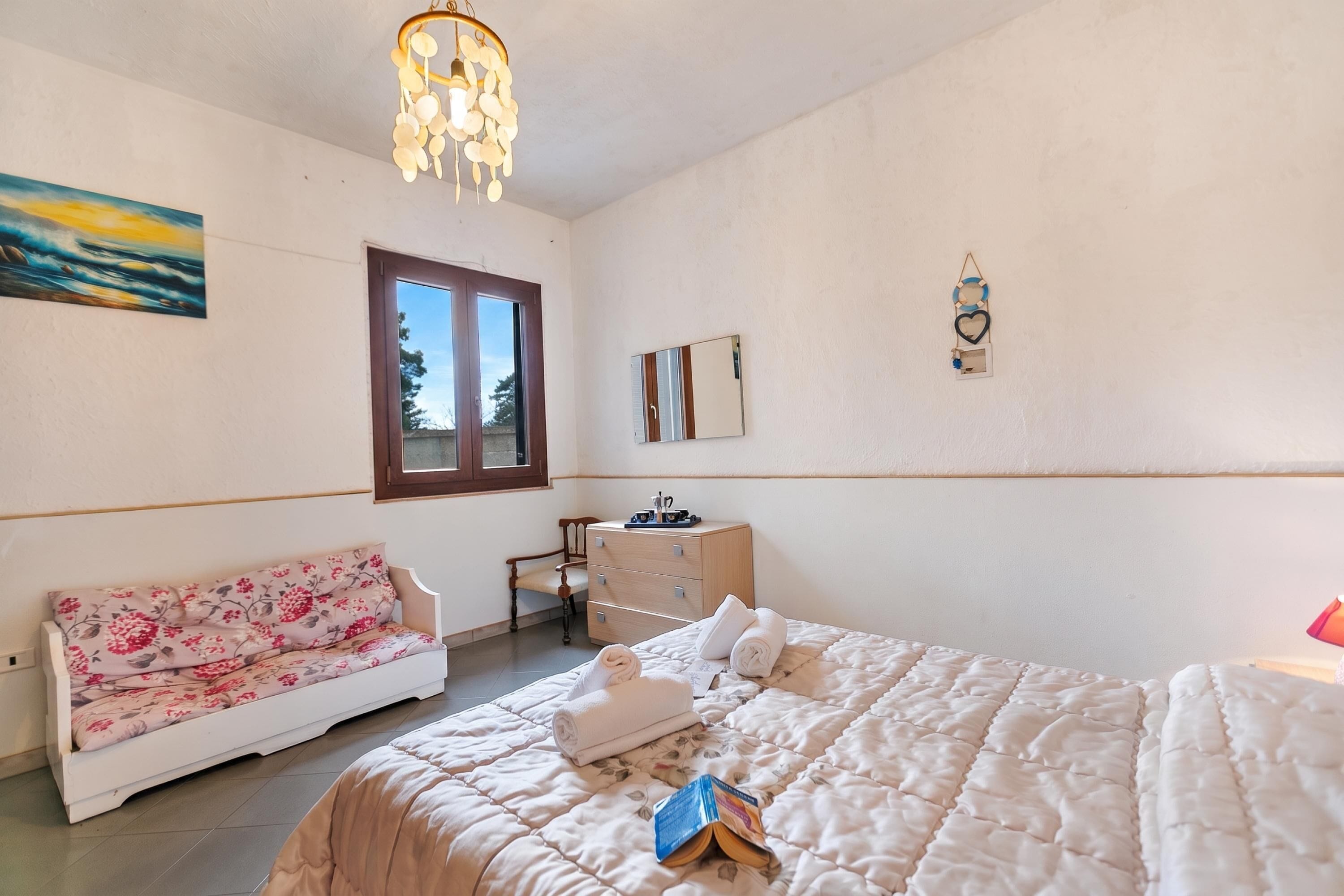 Un dormitorio con cama, sofá, escritorio, silla y ventana.