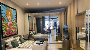A modern hotel room with a bed, seating area, and a view through a glass door to a dining area. - Modern Suite in the Taunus (Bad Camberg)