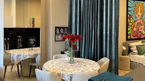 A modern living room with a round table, chairs, a coffee table, and a sofa. There is a dining area with a table and chairs, and a kitchen area with cabinets and a refrigerator. - Modern Suite in the Taunus (Bad Camberg)