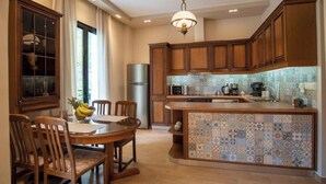 A kitchen with wooden cabinets, a tiled backsplash, a central island, and a dining area with chairs and a table.