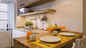 A breakfast setup with a wooden table, plates, cups, and a fruit bowl. - Luxury Apartment Lina - I (Dubrovnik)