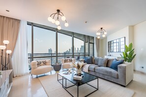 A modern living room with a large window, a sofa, a coffee table, and a plant.