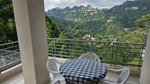 Un balcón con mesa y sillas, con vistas a una colina con edificios.