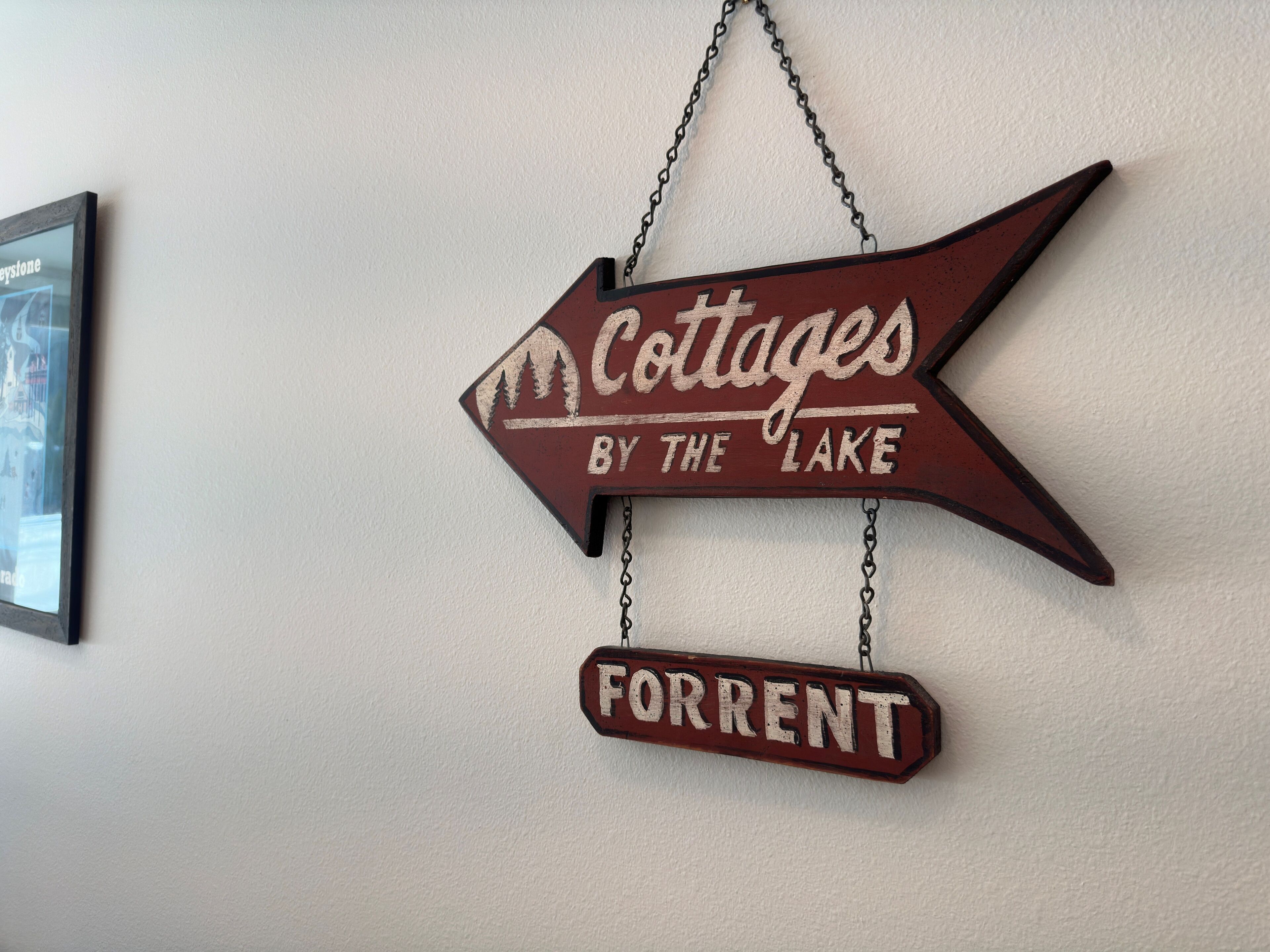 A directional sign with the text "Cottages by the Lake" and "Forrent" indicating a location.