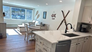 A modern kitchen with a central island, white cabinetry, and a large window providing a view of the neighborhood. - Beautiful Renovated 1br Lakeside Condo 1 Bedroom Condo (Keystone)