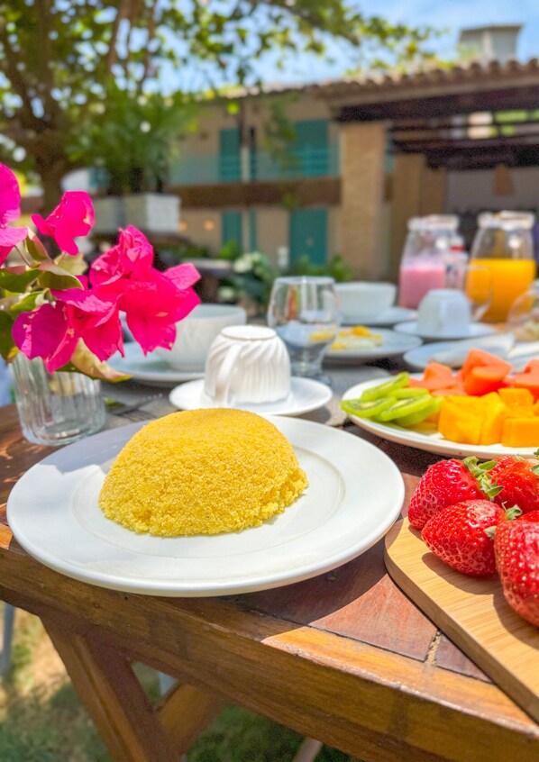 A table set with a yellow dish, fresh strawberries, and a variety of fruits and vegetables. - Amaly Pousada e Bistrô (Japaratinga)