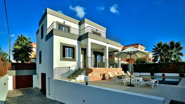 A modern two-story house with a swimming pool, outdoor seating, and a stone wall. - Amazing Villa Near Ibiza Town (Santa Eulalia del Rio)