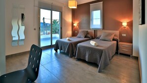 A modern hotel room with two beds, a balcony, a chair, and a desk. - Amazing Villa Near Ibiza Town (Santa Eulalia del Rio)