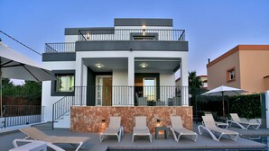 A modern two-story house with a swimming pool, outdoor seating, and a stone wall. - Amazing Villa Near Ibiza Town (Santa Eulalia del Rio)