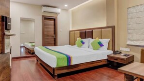A hotel room with a wooden bed, a nightstand, a desk, and a ceiling fan.