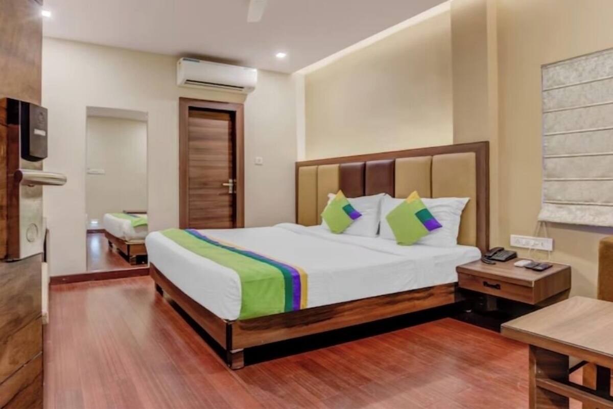 A hotel room with a wooden bed, a nightstand, a desk, and a ceiling fan.