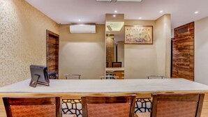 A conference room with a long table, chairs, an air conditioning unit, and a decorative wall piece.