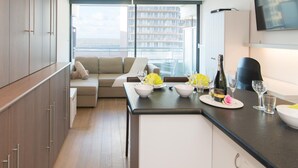 Eine moderne Küche mit Essbereich, einer Couch und einem an der Wand befestigten Fernseher.