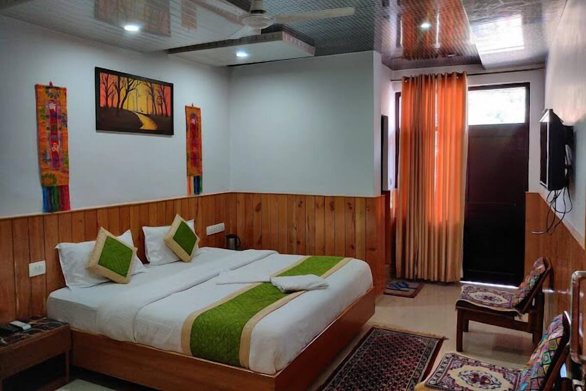 Ein Hotelzimmer mit einem großen Bett, Holzwänden, einem Deckenventilator, einem Fernseher und einem Fenster mit Vorhängen.