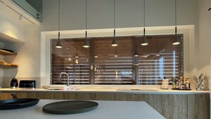 A modern kitchen with a central island, pendant lights, a large window with blinds, and a wooden countertop. - Ultra-luxurious 6-bedroom villa with AC, WiFi in marvelous Piemonte (Piemonte)
