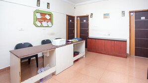 Een kamer met een bureau, stoelen, een prikbord en een kast.