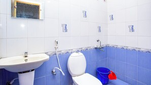 Een badkamer met een witte wastafel, toilet en een blauwe emmer.