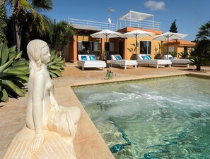 A swimming pool with a statue, lounge chairs, and umbrellas. - Modern Villa With Pool Near Town (Nijar)