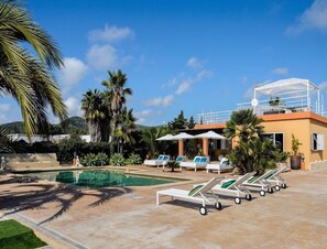 A pool area with lounge chairs, umbrellas, and a building with a balcony. - Modern Villa With Pool Near Town (Nijar)