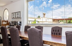 A conference room with a large table and eight chairs, a television, and a view of a building and sky through a large window. - Villa With Salt Water Pool (Palma de Mallorca)