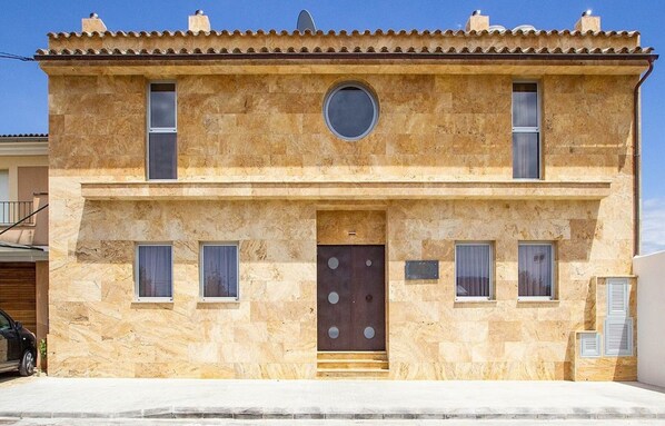 A two-story building with a stone facade, a central entrance with a circular window, and two side windows. - Villa With Salt Water Pool (Palma de Mallorca)