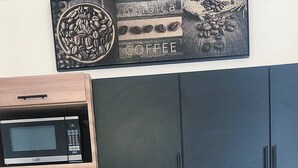 A kitchen with a microwave, coffee maker, and a coffee cup on the counter. - Sweet Sunset II- Rompeolas Beach (Aguadilla)