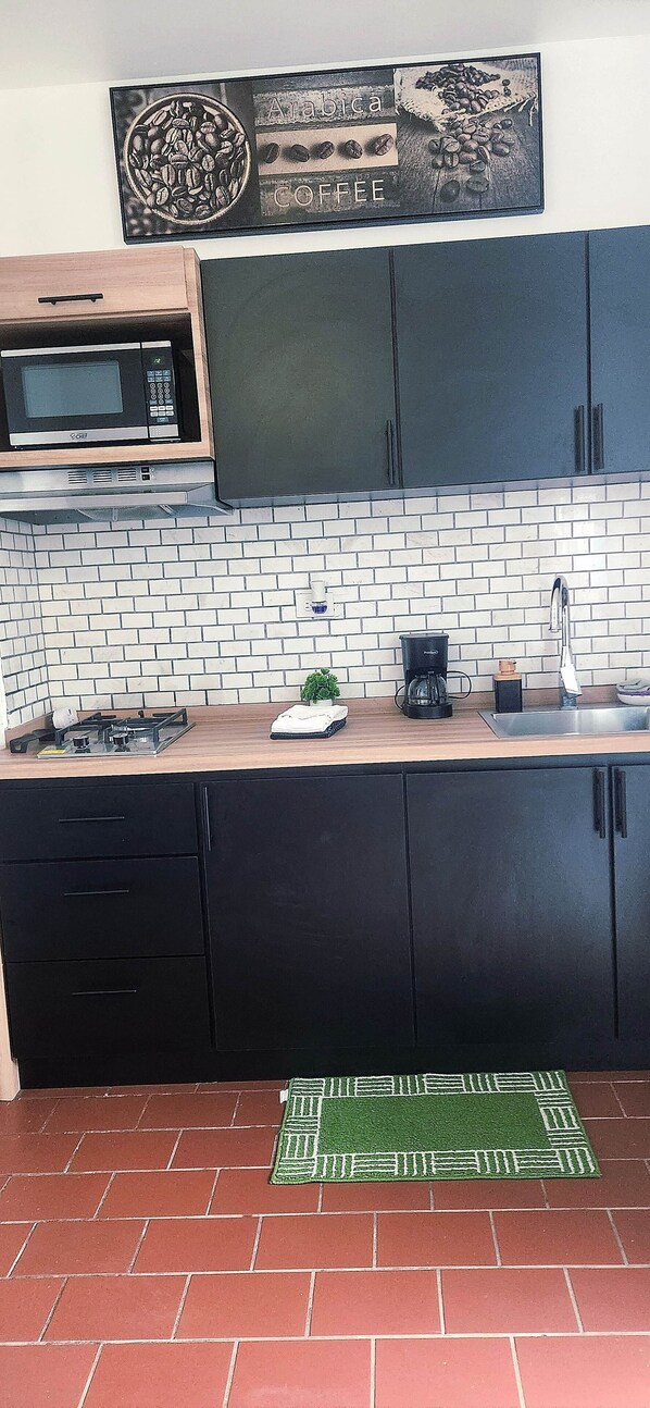 A kitchen with a microwave, coffee maker, and a coffee cup on the counter.