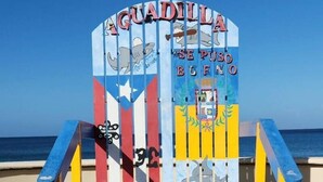 A colorful beach chair with a sign that reads "AGUADILLA SE PUSO BUENO" and features a shark and a coat of arms. - Sweet Sunset II- Rompeolas Beach (Aguadilla)