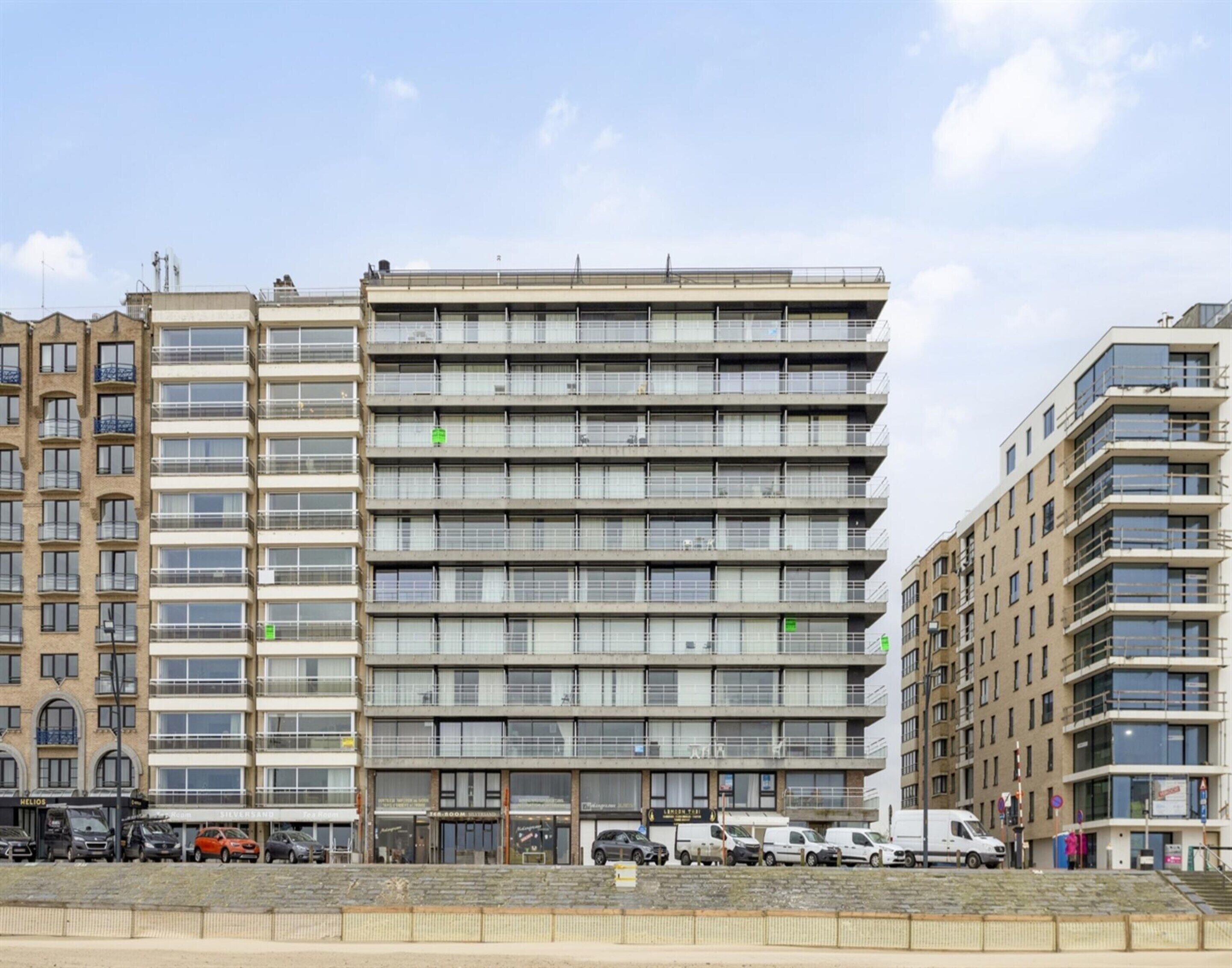 Ein mehrgeschossiges Gebäude mit moderner Architektur, das eine Reihe von Balkonen und großen Fenstern aufweist.