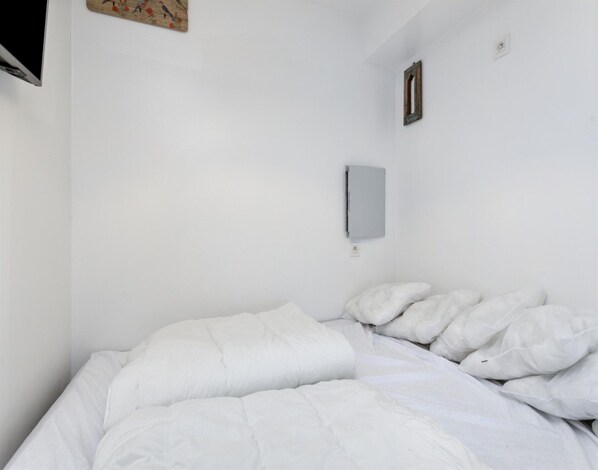 A white room with a bed, a wall-mounted light, and a small picture frame. - Studio in Blankenberge With Stunning Sea View (Blankenberge)