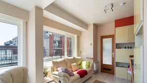 Een woonkamer met een bank, een stoel, een eettafel en een keuken.