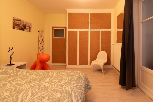 Un dormitorio con cama, una silla, un armario y una puerta.