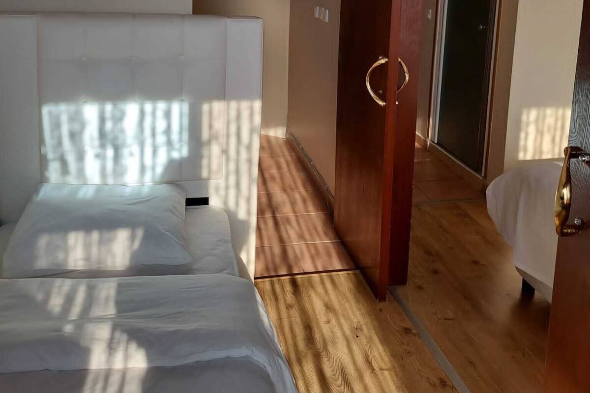 Una habitación de hotel con una cama grande, suelo de madera y una puerta corredera que da a otra habitación.