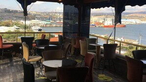 A restaurant with outdoor seating overlooking a harbor, featuring a wooden deck and hanging pendant lights. - GOLDEN ELİT OTEL (Bandirma)