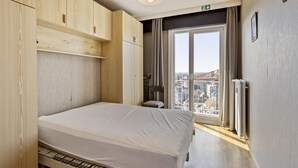 Ein modernes Schlafzimmer mit einem hölzernen Bett, Einbauschrank und einem großen Fenster mit Blick auf die Stadt.