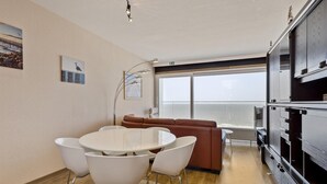 Ein modernes Wohnzimmer mit einem runden Esstisch, weißen Stühlen, einem braunen Sofa und einer großen, schwarzen Unterhaltungseinheit.