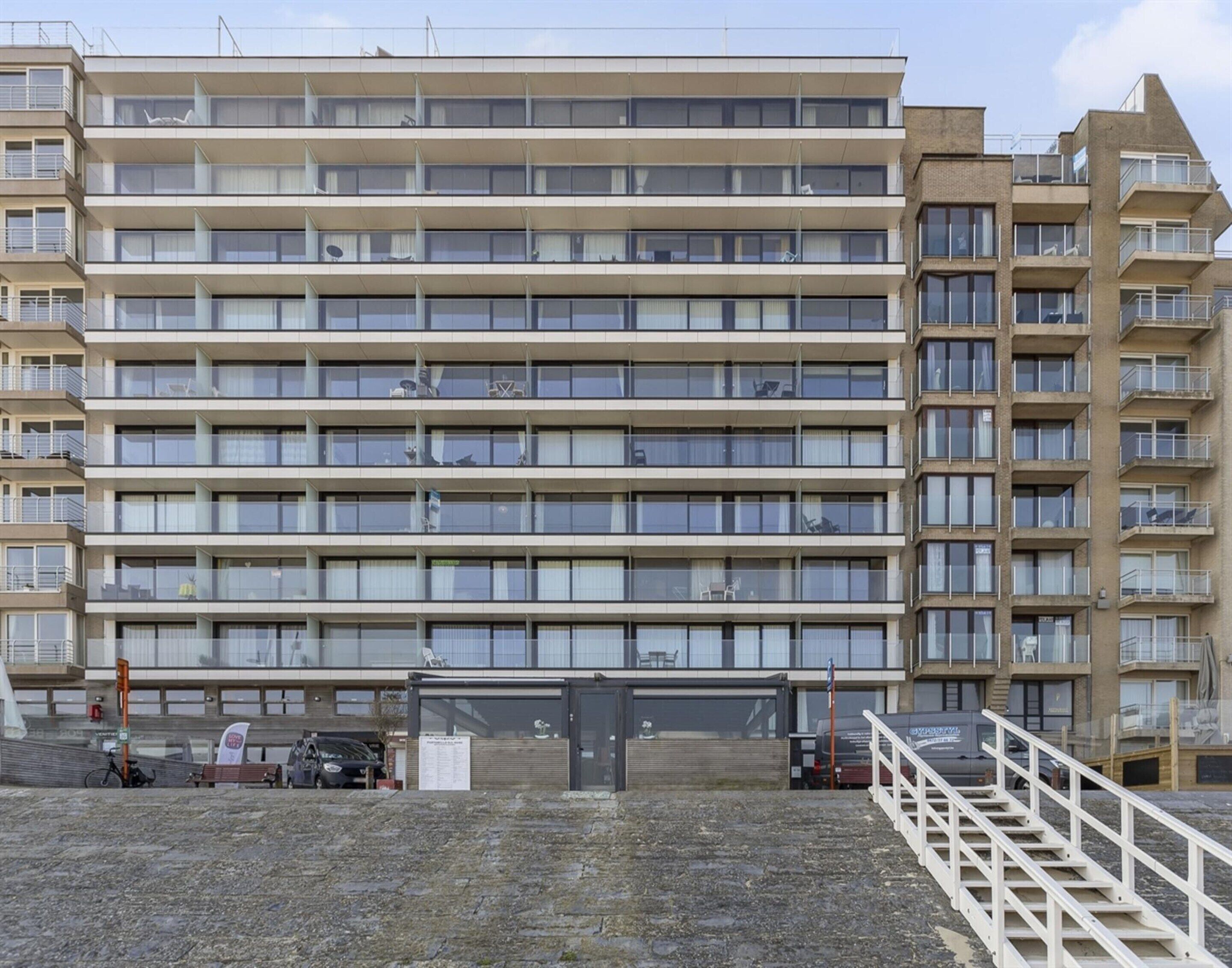 A multi-story building with a uniform facade, balconies, and a gated entrance.