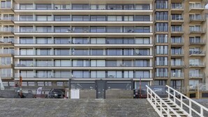 Ein mehrstöckiges Gebäude mit einheitlicher Fassade, Balkonen und einem geschlossenem Eingangsbereich.