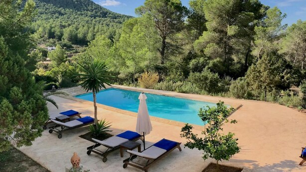 A pool area with lounge chairs and umbrellas, surrounded by trees and a mountain in the background. - Villa With Private Pool (Sant Cebria de Vallalta)