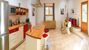 A modern kitchen with a wooden island, built-in appliances, and a dining area with a wooden table and bar stools. - Villa With Private Pool (Sant Cebria de Vallalta)