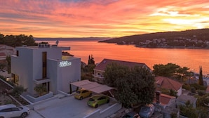 Eine moderne Villa mit Blick auf einen See bei Sonnenuntergang.