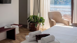 Ein Hotelzimmer mit Bett, Sessel, Fernseher, Pflanze und Meerblick.