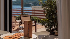 Ein Balkon mit Tisch und Stühlen, Blick aufs Meer und Geländer.