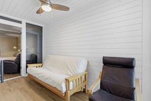 A room with a wooden bed, a dark leather chair, and a ceiling fan.