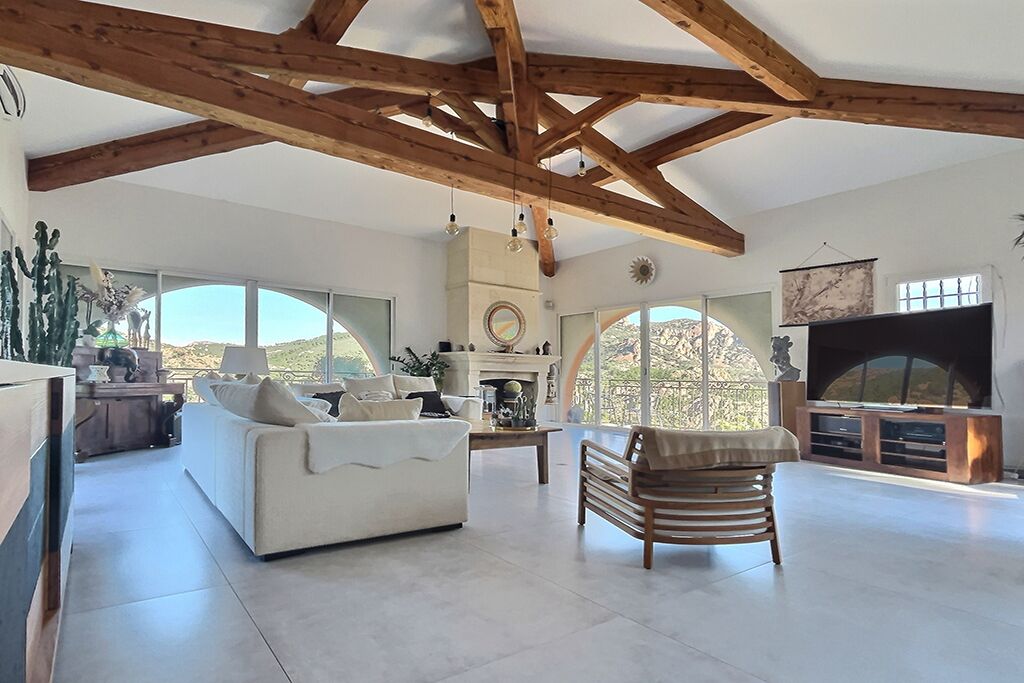 Amplia sala de estar con techo alto, chimenea, televisor grande y vistas al exterior.